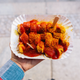 aerial view of a hand holding a paper plate of currywurst